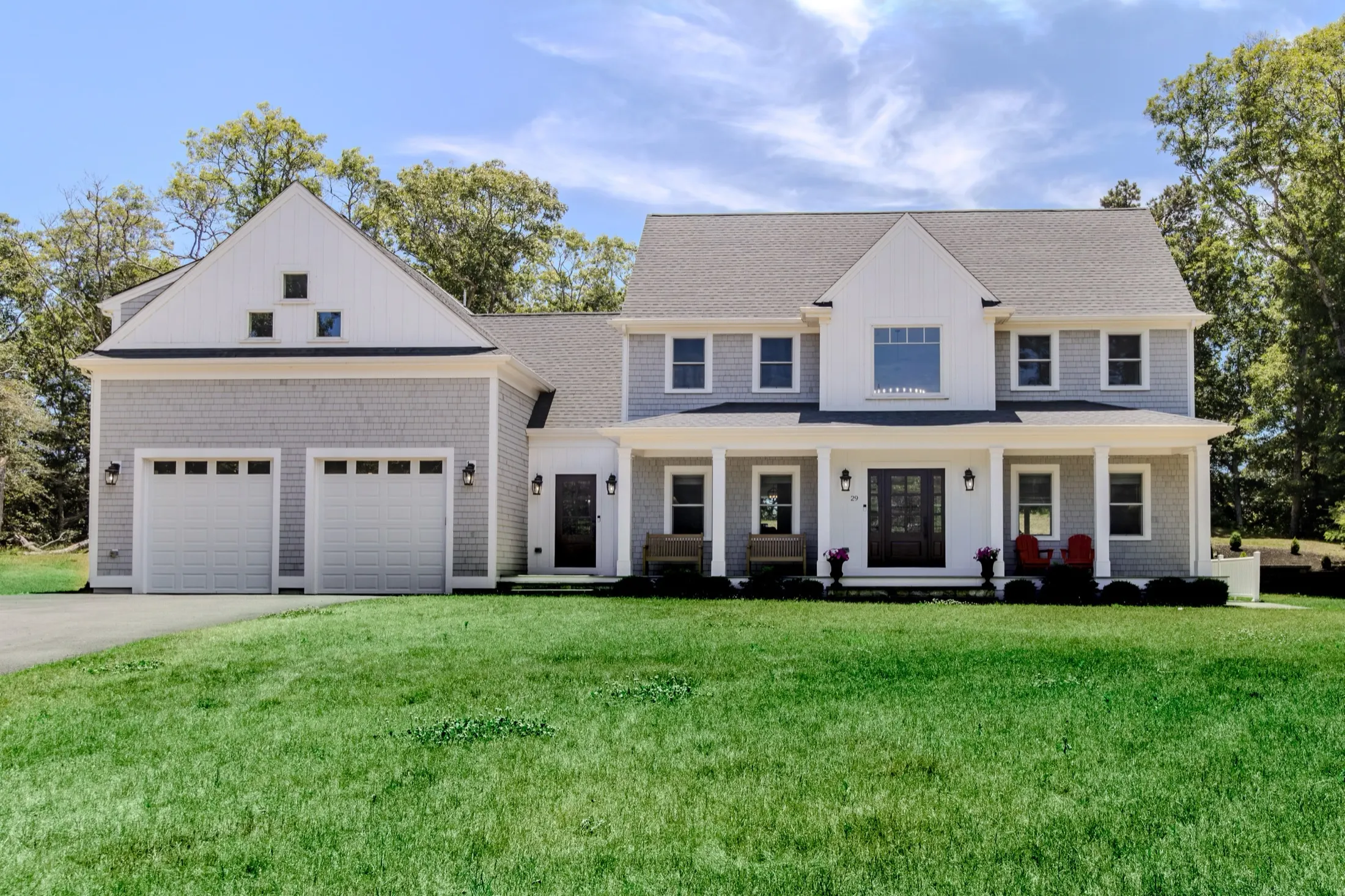 The front of Lakewind House, a grey-shingled Cape Cod home set among tall trees.